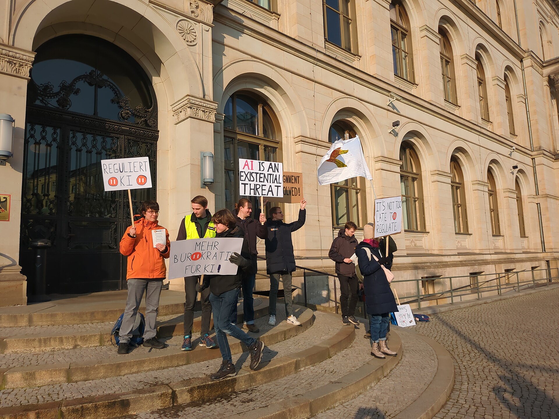 A real protest against the February 2025 AI Action Summit, demonstrators with signs outside the BMDV building in Berlin.