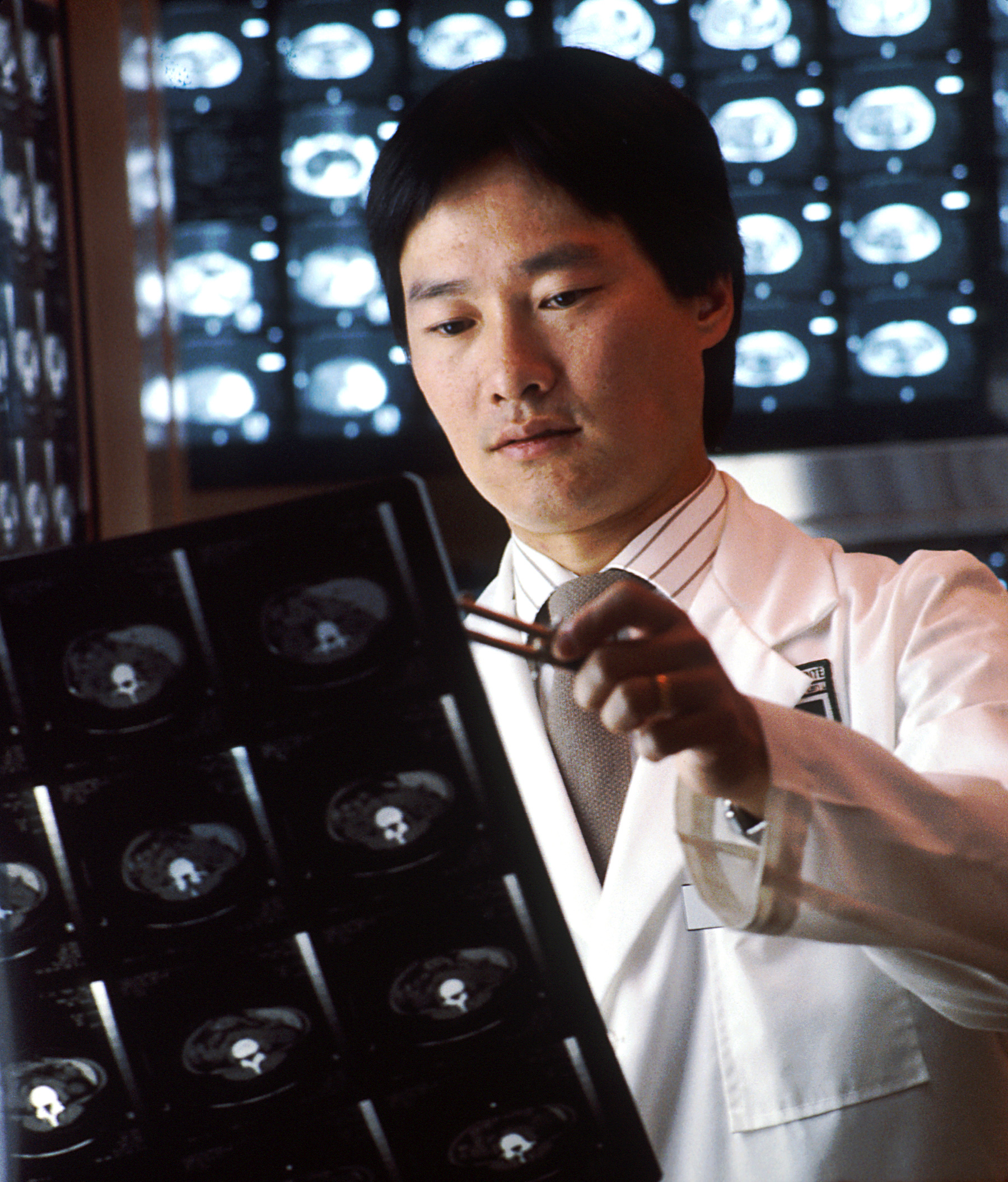 A radiologist reviewing computed tomography scans on a diagnostic workstation. AI-assisted medicine doing quiet, measured work.